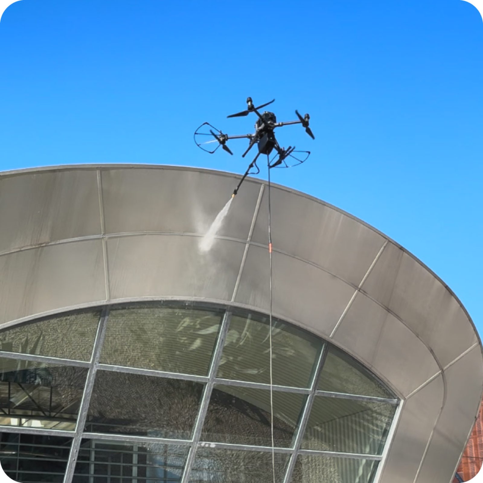 Drone con lancia che lava la copertura metallica curva di un edificio